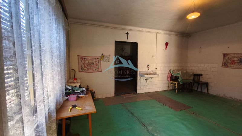 Einfaches Zimmer in einem Einfamilienhaus mit Waschbecken und Vorhängen an den Fenstern.