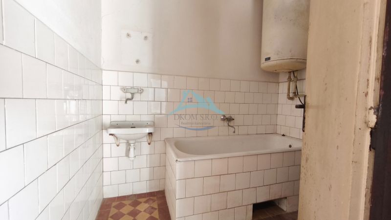 Badezimmer in einem Einfamilienhaus mit Badewanne, weißen Fliesen und einem Wassererhitzer.