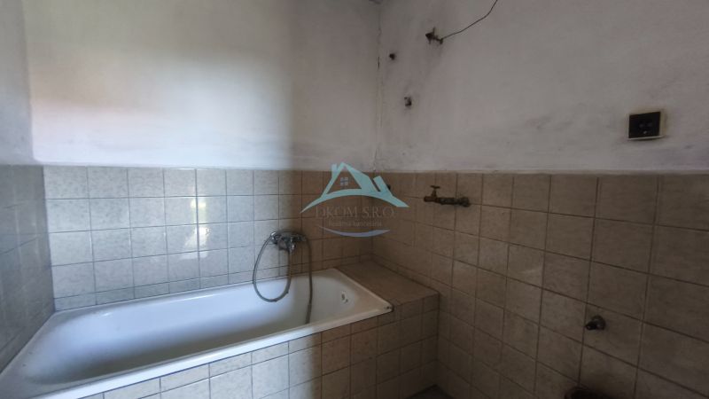 Ein Badezimmer in einem Einfamilienhaus mit einer Badewanne, die mit hellen Fliesen verkleidet ist.