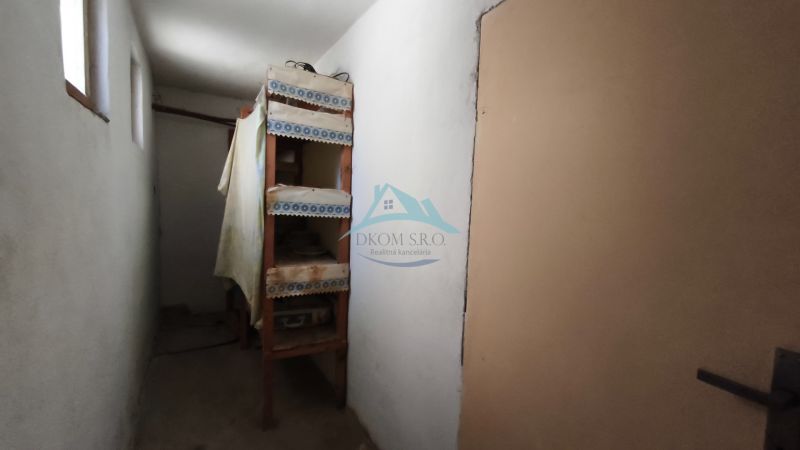 Ein schmaler Flur mit Regalen in einem Einfamilienhaus, einfache Einrichtung.
