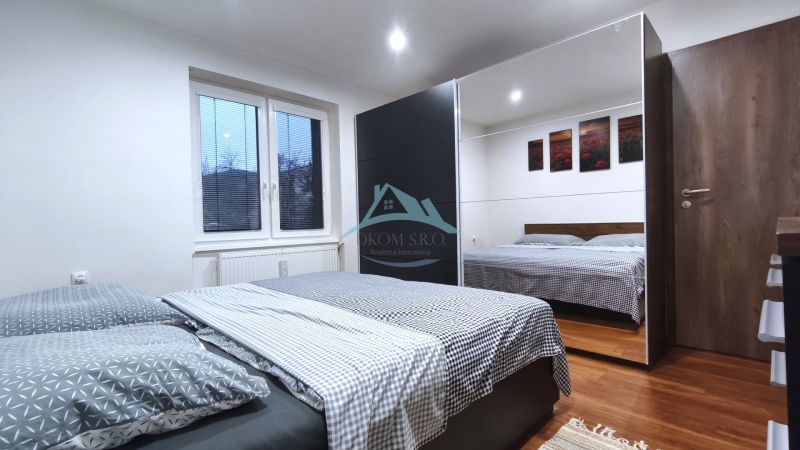 Ein Schlafzimmer in einem Einfamilienhaus mit einem Bett, einem großen Schrank und einem Boden in Holzoptik.