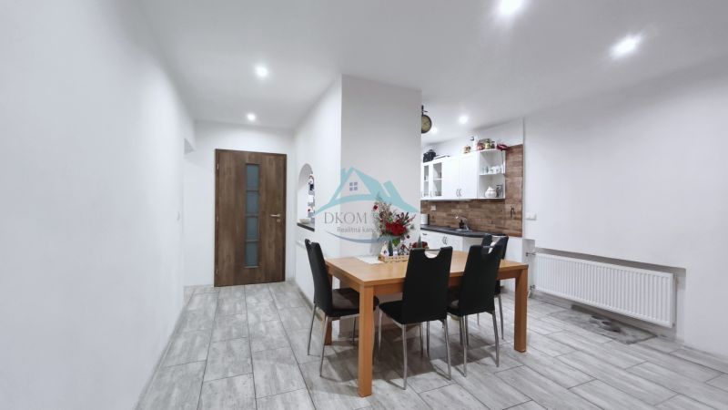 Esszimmer in einem Einfamilienhaus mit Holztisch, schwarzen Stühlen und Küchenzeile.