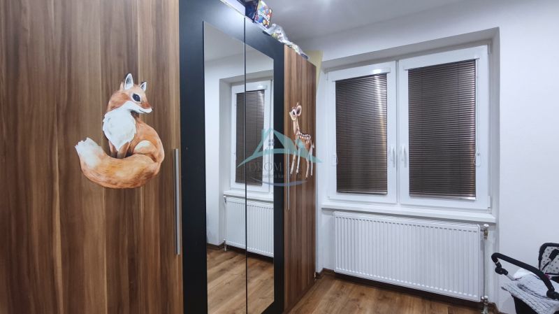 Schrank mit Tierdekoren im Einfamilienhaus, Holzboden, Heizkörper unter dem Fenster mit Rollläden.