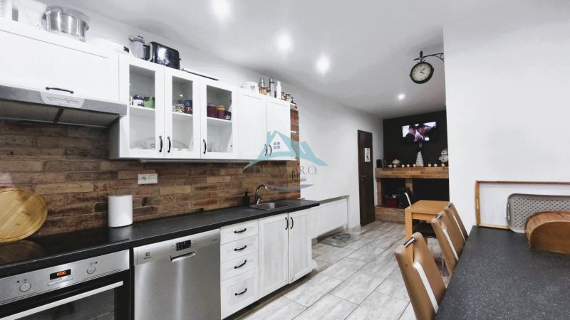 Küche in einem Einfamilienhaus mit ländlicher Ziegelverkleidung und weißen Schränken, Boden mit Holzdekor.