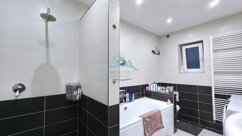 Ein Badezimmer im Einfamilienhaus mit Badewanne, Dusche und weißen Fliesen.