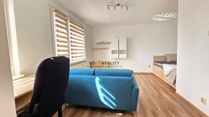 Einzimmerwohnung mit blauem Sofa, Bett und Boden in Holzoptik.