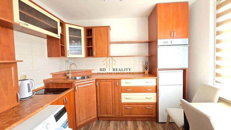Die Küche einer Einzimmerwohnung mit Holzschränken und einem Boden in Holzoptik.