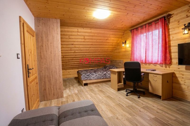 Ein Zimmer in einem Einfamilienhaus mit Holzwänden, einem Boden mit Holzdekor und einem Schreibtisch.