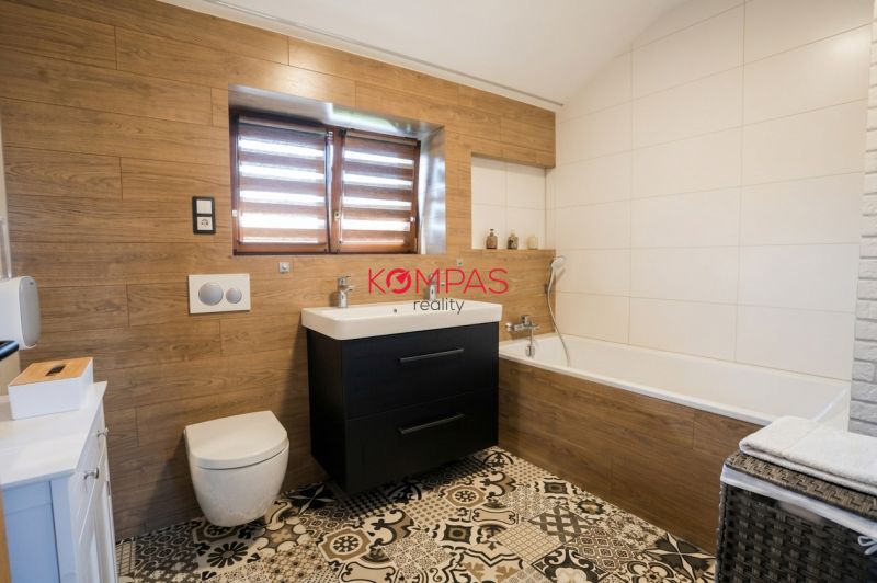 Ein Badezimmer in einem Einfamilienhaus mit einer Badewanne, einem Waschbecken und einem Boden mit Holzdekor.