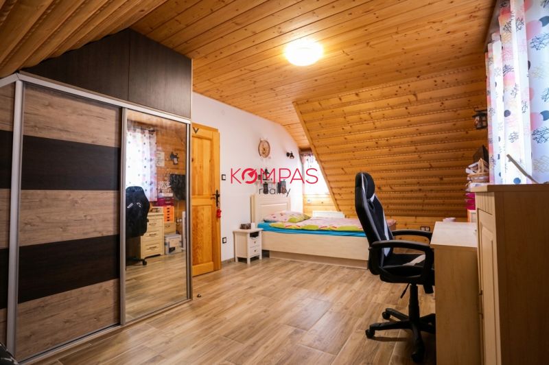 Dachzimmer mit Holzverkleidung an der Decke, Bett, Schrank und Boden mit Holzdekor.