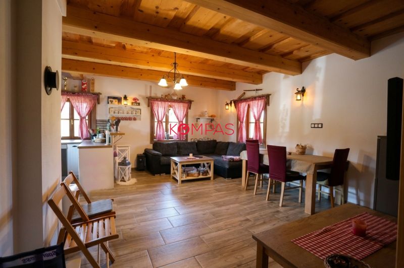 Wohnzimmer eines Einfamilienhauses mit Holzdecken, einem Boden in Holzoptik und roten Vorhängen.