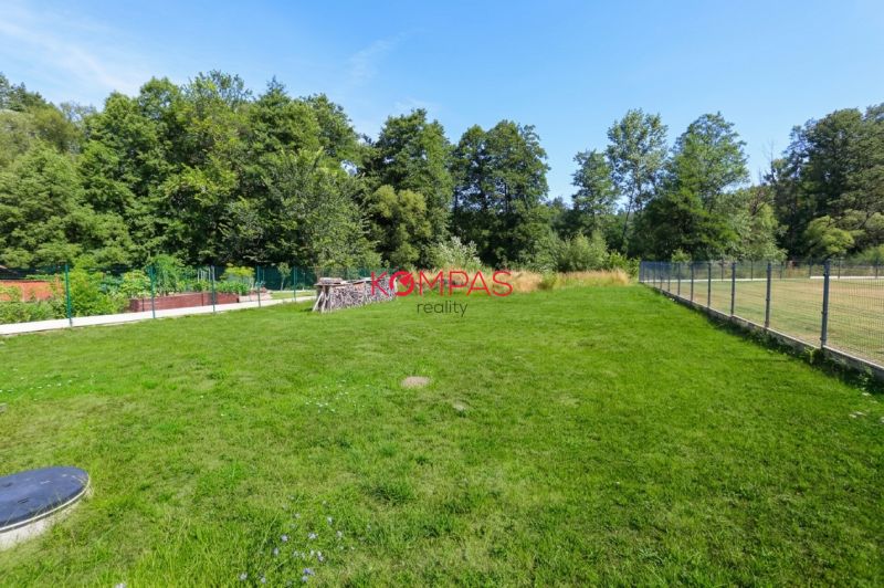 Der Garten des Einfamilienhauses in Očová mit Rasen und Umzäunung, umgeben von Wald.