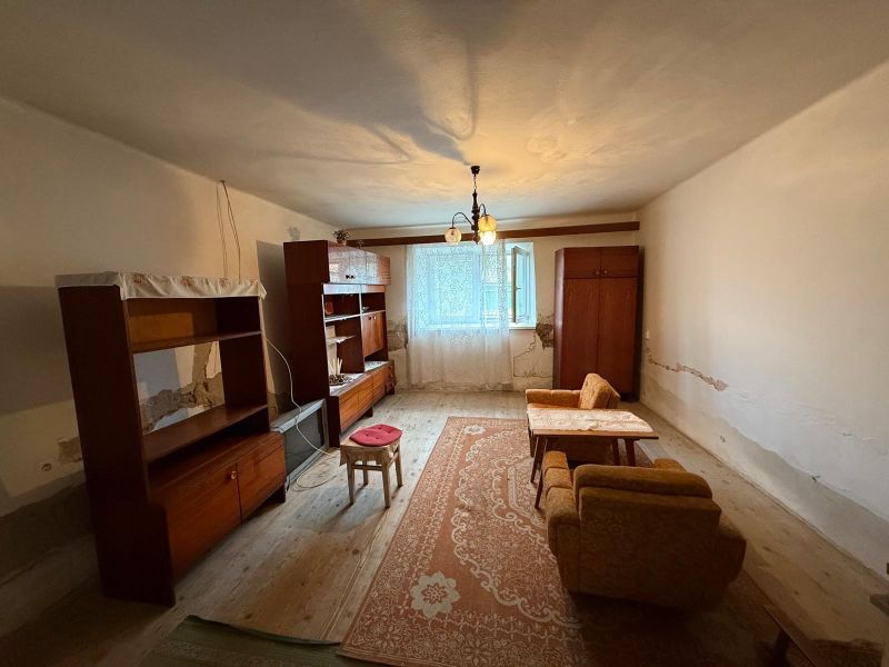 Ein Zimmer in einem Einfamilienhaus mit Möbeln auf einem Boden mit Holzdekor und einem Teppich.