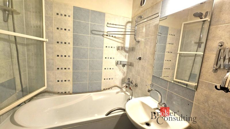 Badezimmer in einer 4-Zimmer-Wohnung mit Badewanne, Waschbecken und blauen Fliesen.