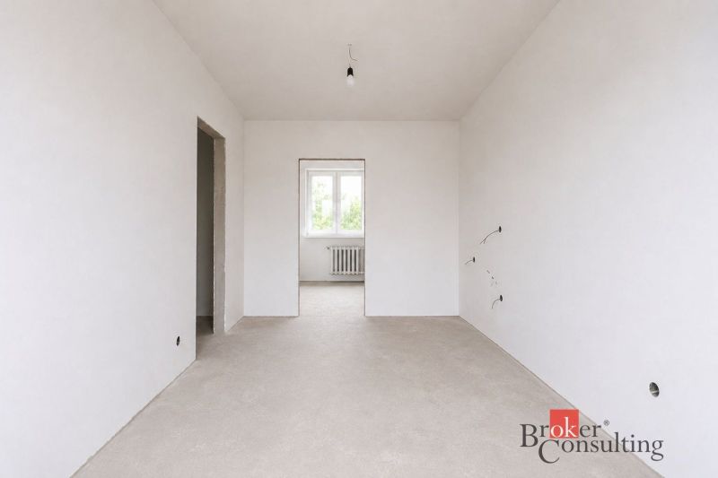 Ein leerer Raum in einer Vierzimmerwohnung mit weißen Wänden und einem Fenster.