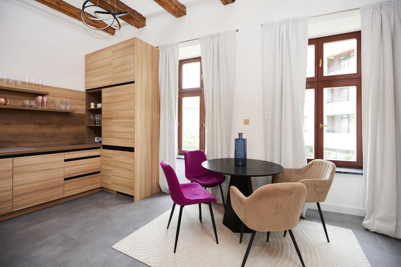 Küchenecke in einer 3-Zimmer-Wohnung mit bunten Stühlen und einem Boden in Holzoptik.