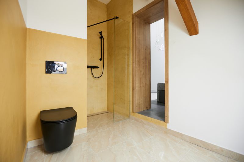Badezimmer mit gelben Wänden, schwarzer Toilette und Duschkabine in einer 3-Zimmer-Wohnung.