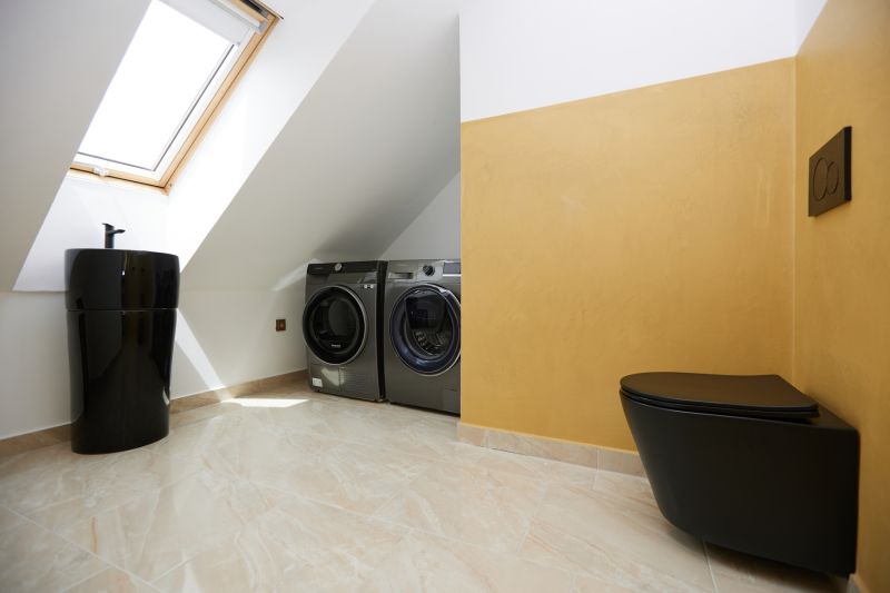 Badezimmer mit schwarzer Toilette, Waschbecken und Waschmaschinen in einer 3-Zimmer-Wohnung.