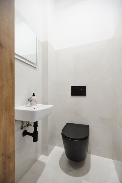 Badezimmer mit schwarzer Toilette, Waschbecken und Spiegel in einer 3-Zimmer-Wohnung.