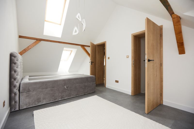Helles Schlafzimmer mit Bett, schrägen Dachfenstern und Holzelementen in einer 3-Zimmer-Wohnung.