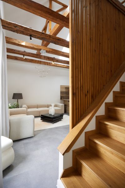 Eine Treppe mit einem Boden in Holzoptik, die in das Wohnzimmer einer 3-Zimmer-Wohnung führt.