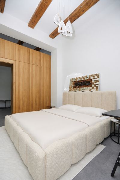 Schlafzimmer in einer 3-Zimmer-Wohnung mit Holzbalkendecke und geräumigem Bett.