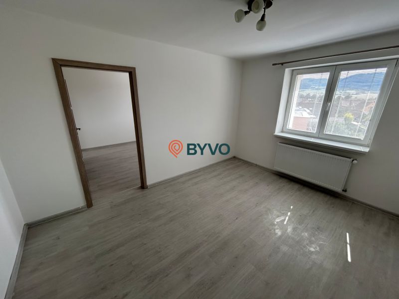 Ein Zimmer mit einem Holzboden, weißen Wänden und einem großen Fenster in einer 3-Zimmer-Wohnung.