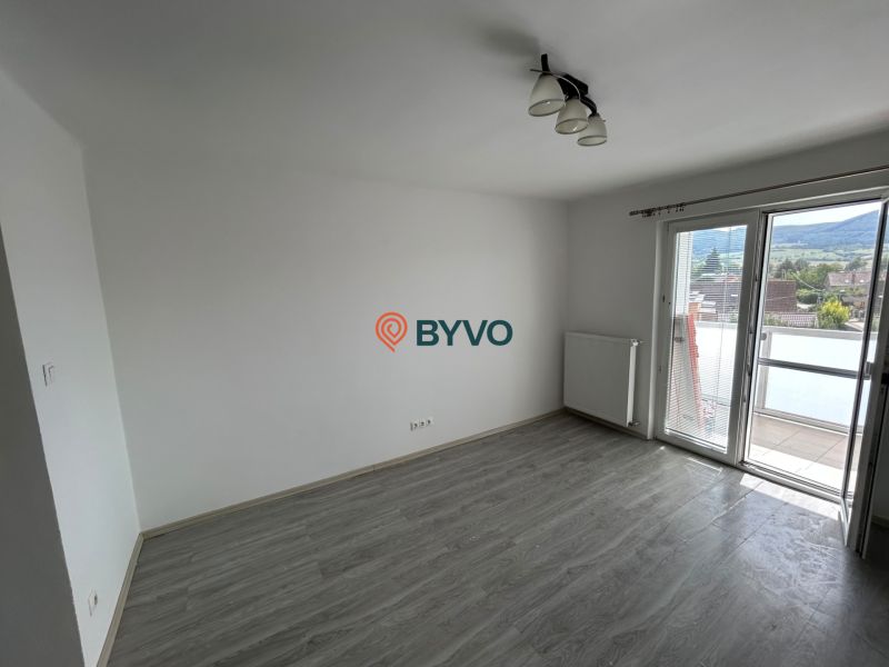Ein Zimmer mit Holzboden und Balkon in einer 3-Zimmer-Wohnung.