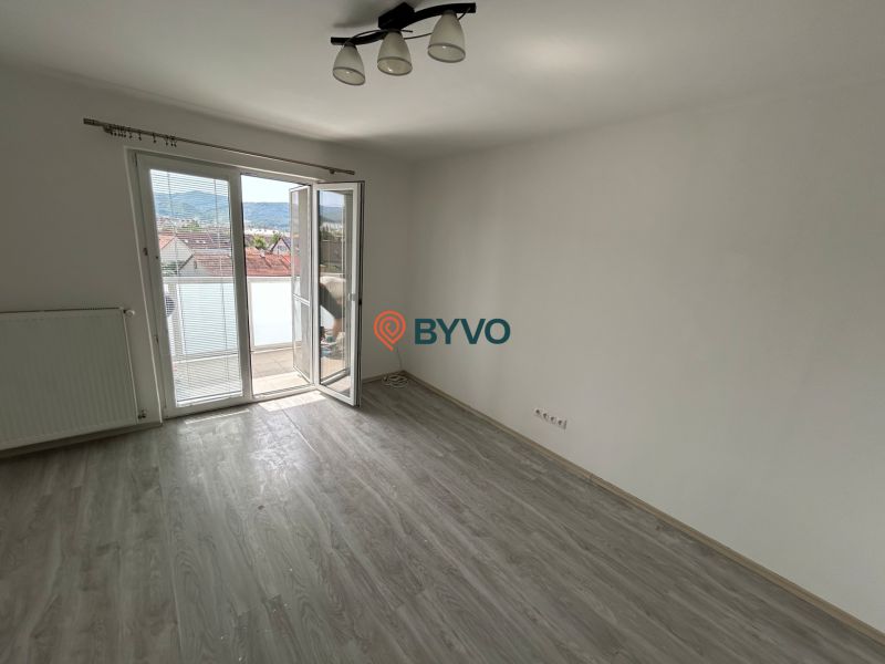 Ein Zimmer in einer 3-Zimmer-Wohnung mit Holzboden und Balkon.