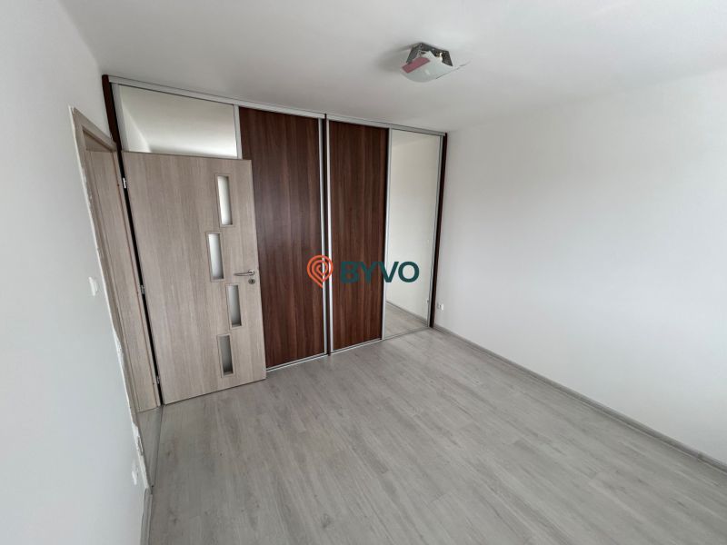 Ein leerer Raum in einer 3-Zimmer-Wohnung mit Holzboden und Einbauschrank.