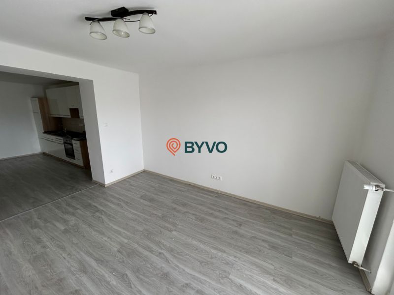 Wohnzimmer einer 3-Zimmer-Wohnung mit Holzboden und Küche auf der linken Seite.