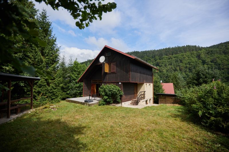 Das Haus in der Straße Rovné 61, Jaklovce, umgeben von Grün und Wald, mit einer Außensitzgelegenheit.