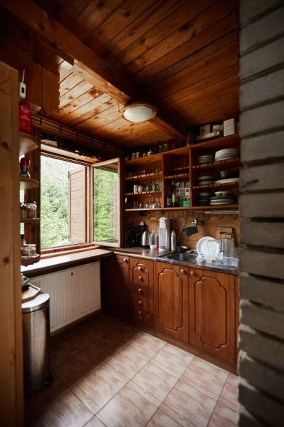 Eine Hütte mit einer rustikalen Küche, Holzmöbeln und einem Blick nach draußen durch das offene Fenster.