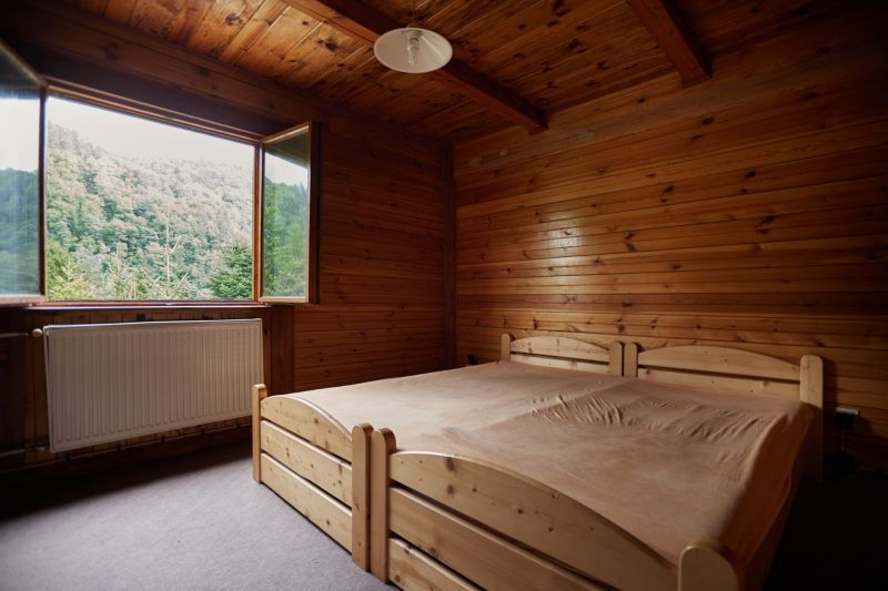 Holzinterieur mit Bett und Blick auf den Wald, Hütte.