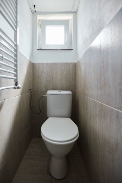 Badezimmer in der Hütte mit Toilette und Fliesen in hellen Farbtönen.