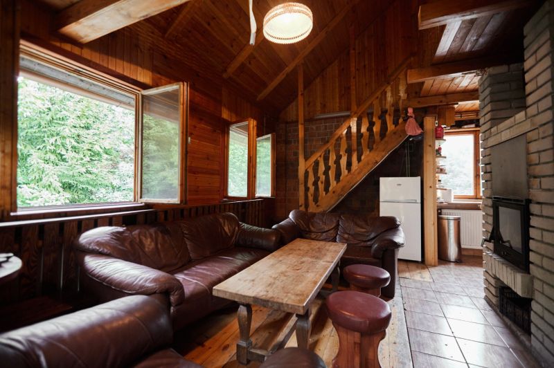 Innenraum einer Hütte mit Ledersofas, Kamin und Holzboden.
