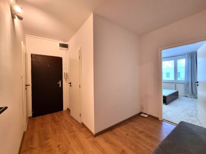 Flur mit Holzboden und Eingang zum Zimmer in einer 2-Zimmer-Wohnung.