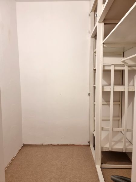Stauraum mit weißen Regalen in einer 2-Zimmer-Wohnung, mit einem Teppichboden.