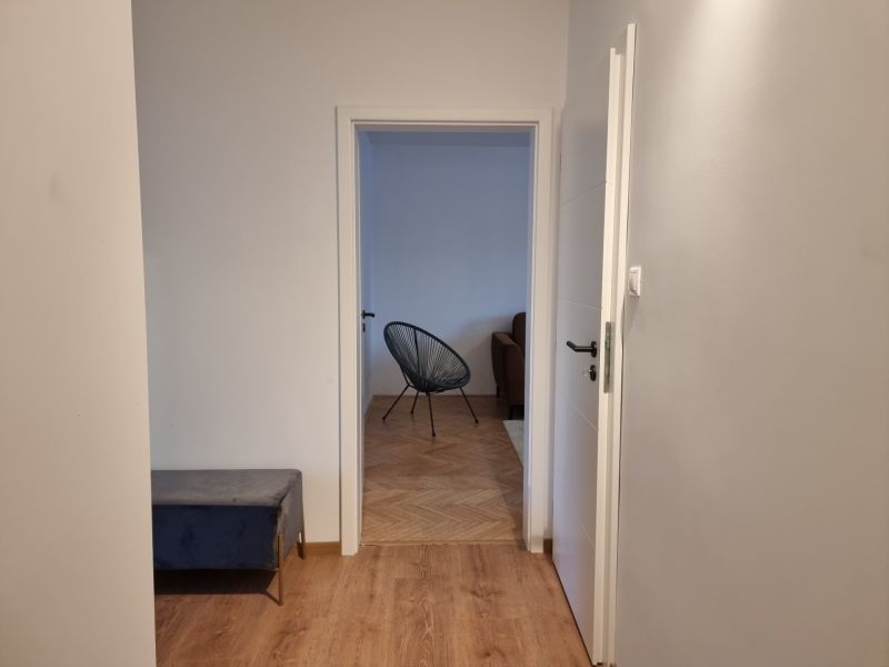 Flur in einer 2-Zimmer-Wohnung mit Holzboden und Blick ins Wohnzimmer.