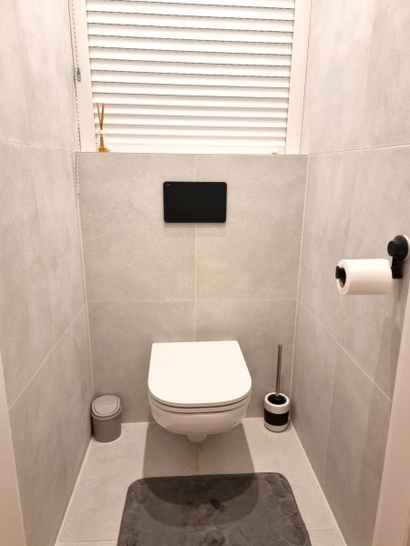 Badezimmer in einer 2-Zimmer-Wohnung mit modernem hängendem WC auf hellen Fliesen.