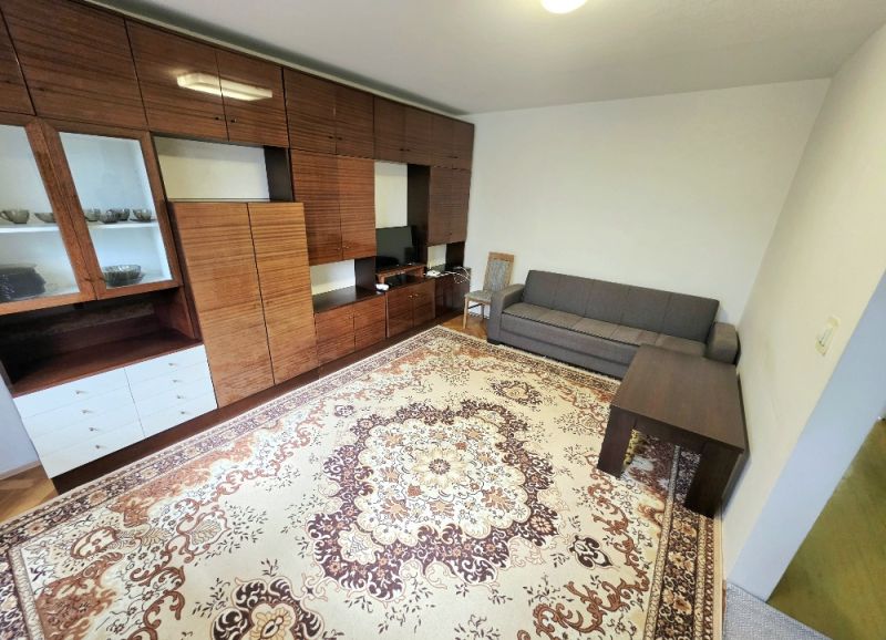 Wohnzimmer in einer 3-Zimmer-Wohnung mit Möbeln und einem Teppich auf einem Boden mit Holzdekor.