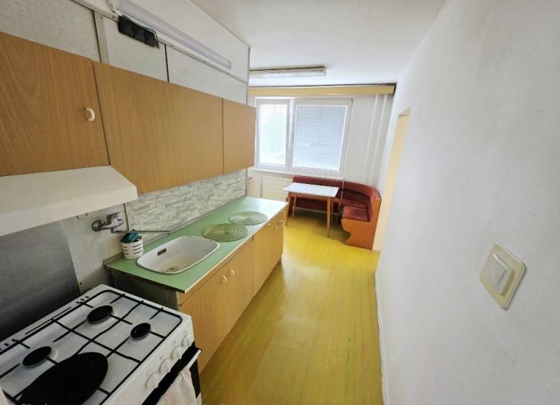 Küche in einer 3-Zimmer-Wohnung mit einfacher Ausstattung, Holzschränken und Essecke.