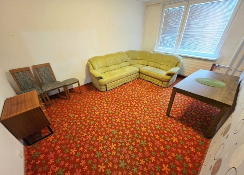 Wohnzimmer in einer 3-Zimmer-Wohnung mit einem Blumenmusterteppich und einer Eckcouch.