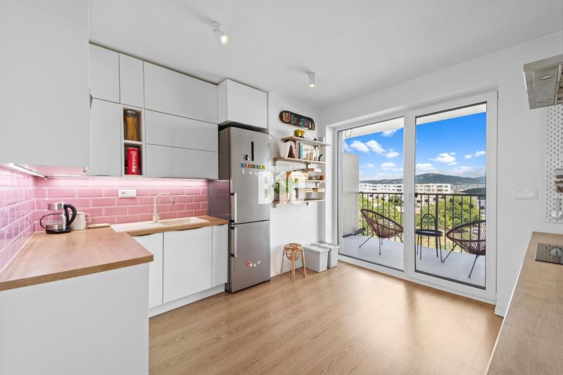 Küche in einer 4-Zimmer-Wohnung mit Balkon und Boden in Holzoptik.