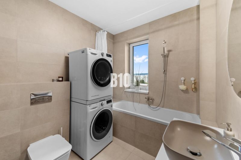Badezimmer mit Dusche, Waschmaschine und Trockner in einer 4-Zimmer-Wohnung, einfaches Design.
