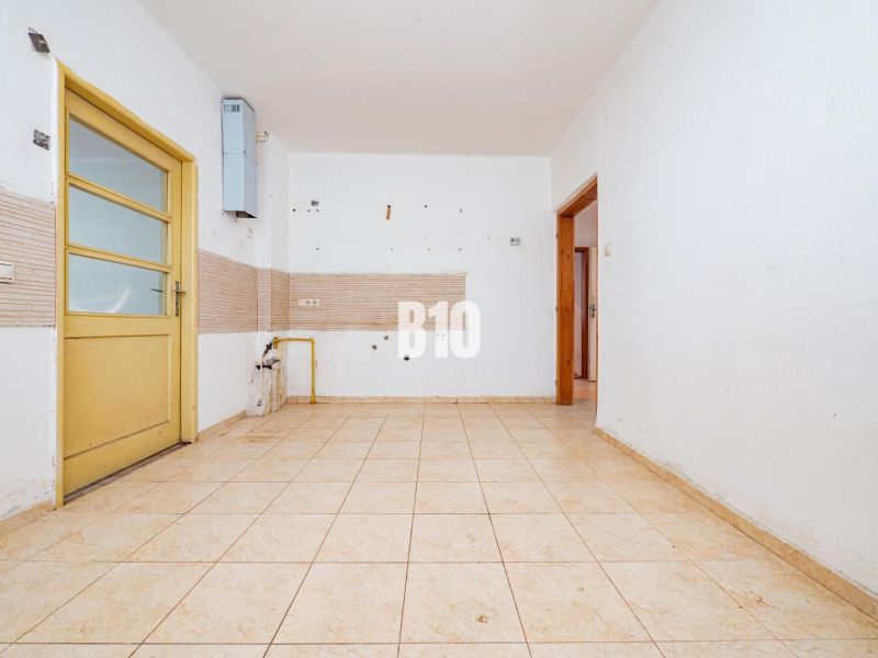 Leerer Raum mit Fliesen und gelber Tür in einem Einfamilienhaus.
