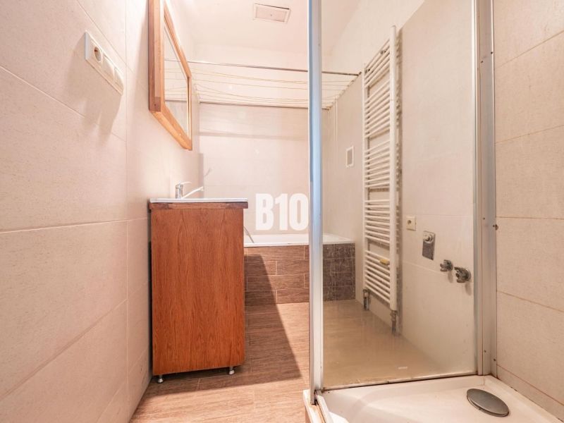 Badezimmer in einem Einfamilienhaus mit Dusche, Waschbecken und Heizkörper, Boden mit Holzdekor.