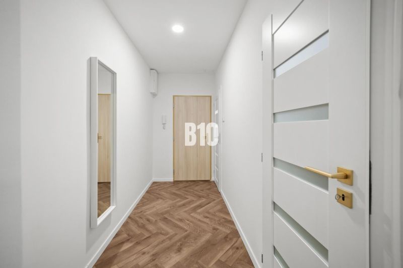 Flur einer 3-Zimmer-Wohnung mit Holzboden und einem Spiegel an der Wand.