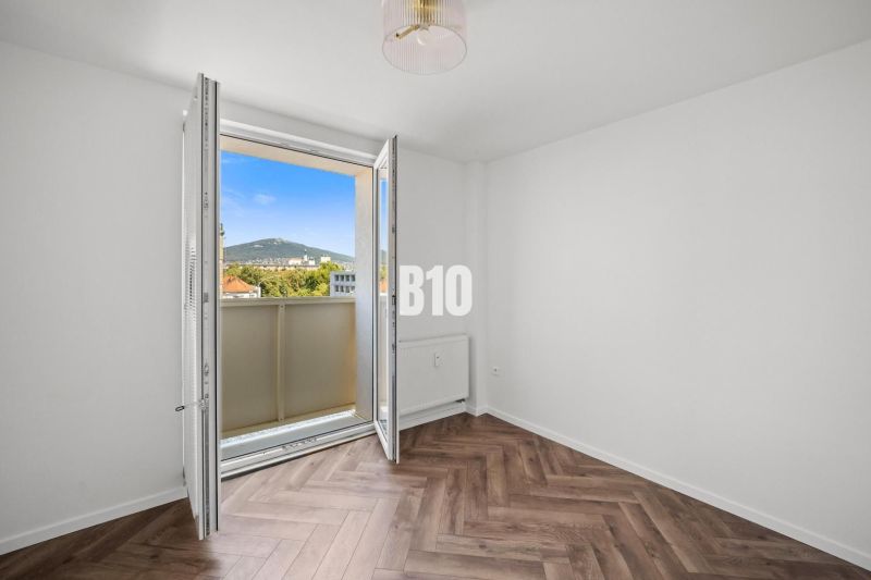 Ein Zimmer in einer 3-Zimmer-Wohnung mit Aussicht und einem Boden in Holzoptik.