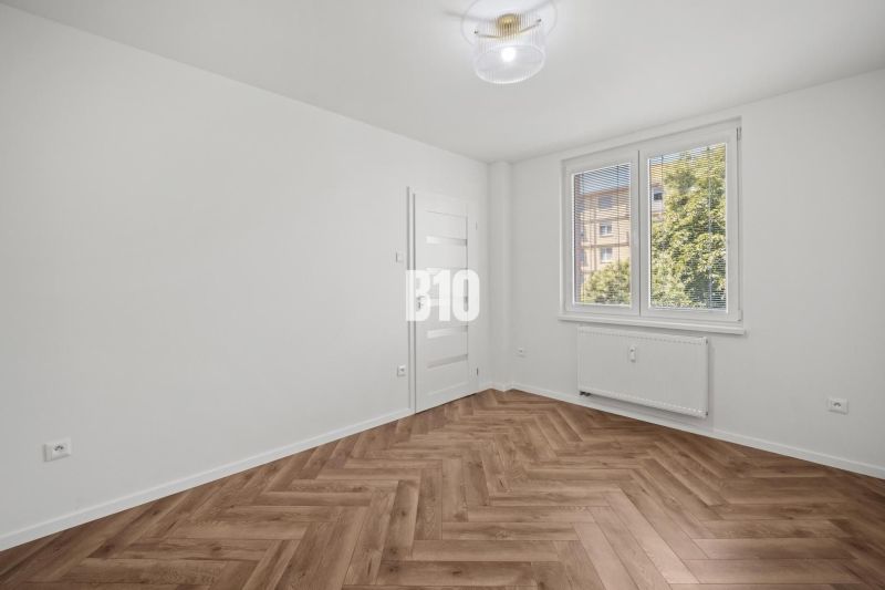 Ein Zimmer in einer 3-Zimmer-Wohnung mit einem Boden in Holzoptik und einem großen Fenster.